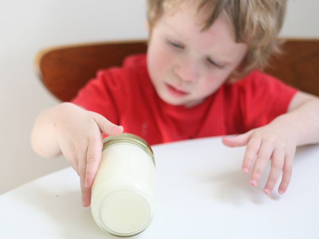 child rolling fresh butter in a mason jar