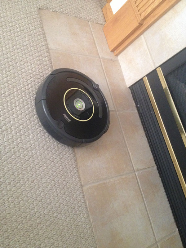 black irobot roomba on tile and carpet