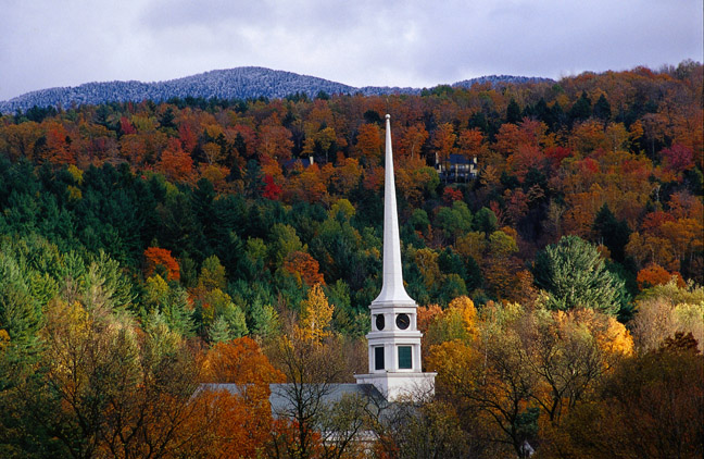 A church spire pierces the autumnal foliage around Stowe - Vermont