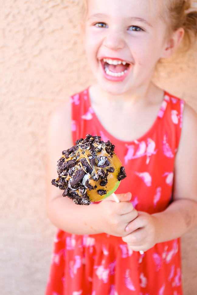 little girl holding an oreo cookie caramel apple