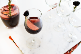 Wine glass with red wine sangria with pitcher of sangria in the background.