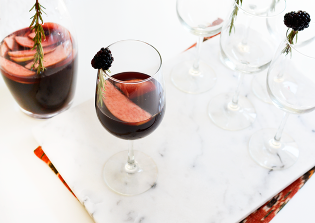 Wine glass with red wine sangria with pitcher of sangria in the background.