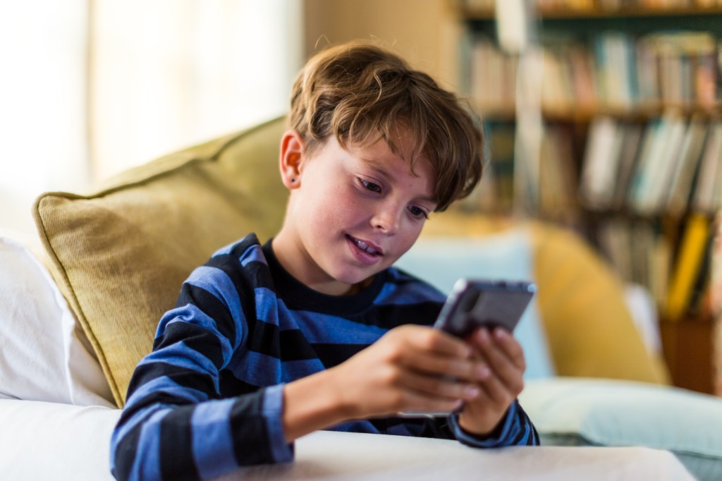 Boy playing alone on smart phone in living room