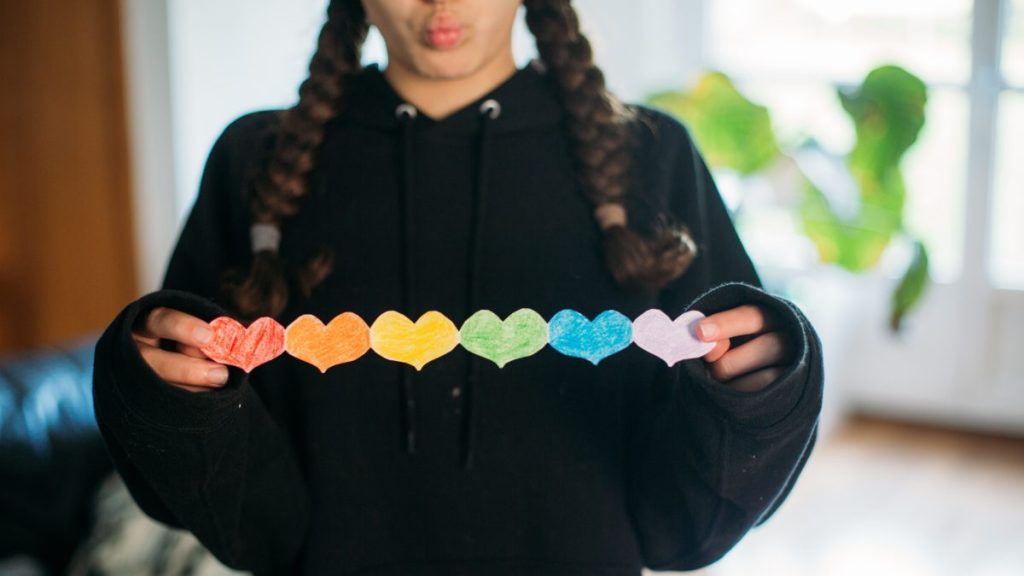 girl holding a paper chain of rainbow hearts