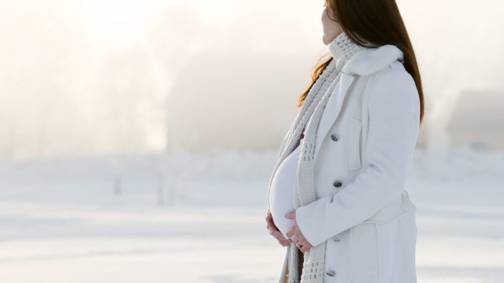 Mother outside in white coat in winter wonderland.