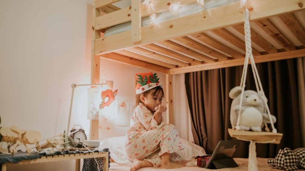 Little girl is watching a cartoon on a digital tablet in her bedroom