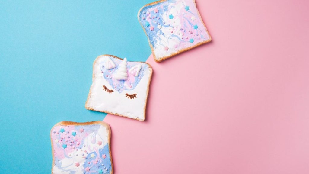 Unicorn and mermaid toasts with stars, food for kids idea, top view on a blue and pink background, a fun recipe you can make with your kids this summer