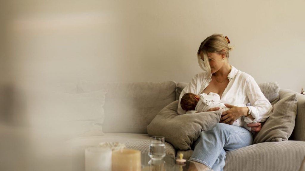 Mother breastfeeding son while sitting on sofa at home