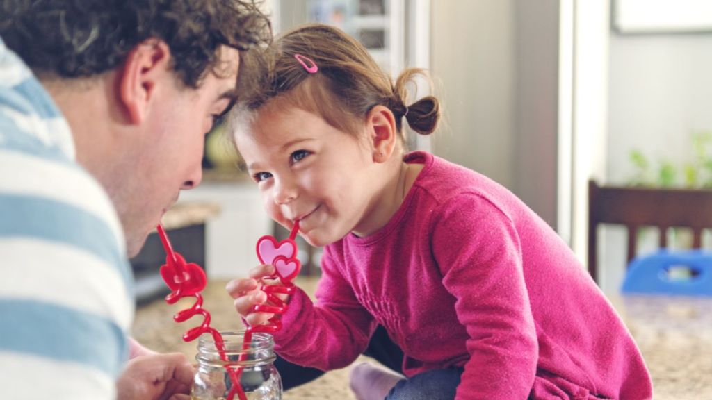 Father and daughter sharing a lemonade using cute Valentine's Day-coded straws.