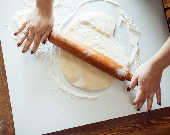 Roll out pizza dough on parchment paper.